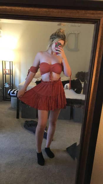 reviewer wearing outfit in rust color while holding skirt out