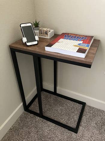 reviewer photo of c-shaped nightstand with book, phone, plant on it