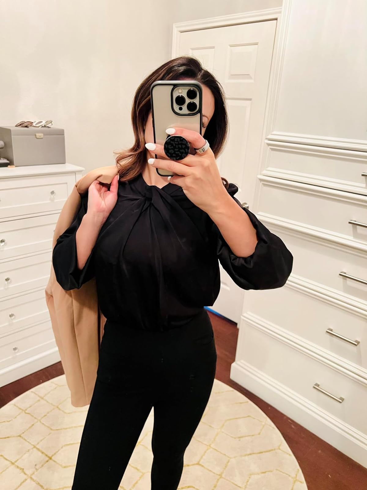 Person wearing a black blouse with twist detail and black trousers