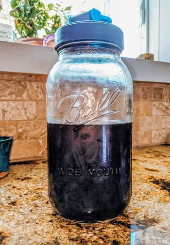 Mason jar with liquid on a kitchen counter, demonstrating a reusable and sustainable option for beverage storage