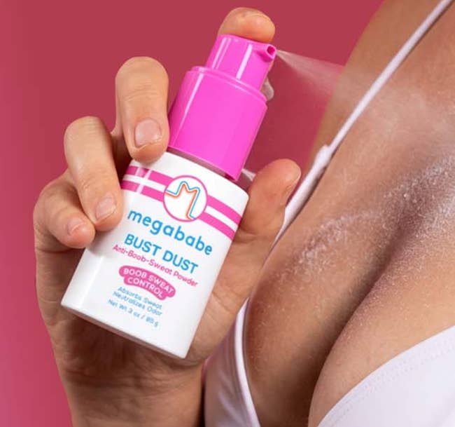 Person applying Megababe Bust Dust anti-sweat pulverization spray to skin. Breast country is visible, showing merchandise usage successful action