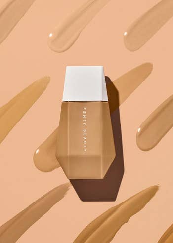 the bottle of fenty beauty skin tint with various shade swatches in the background