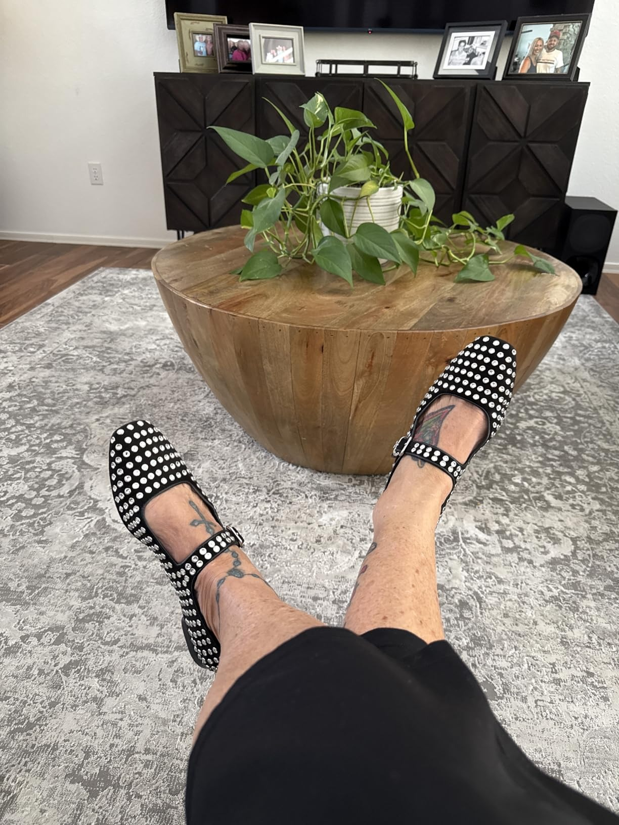 Shot of person's feet wearing achromatic  Mary Jane flats with metallic  studs, with legs crossed