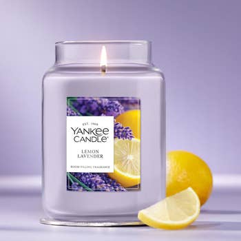 Yankee Candle jar, Lemon Lavender scent, with a statement showing lemons and lavender. A full citrus and lavender flowers are beside the jar