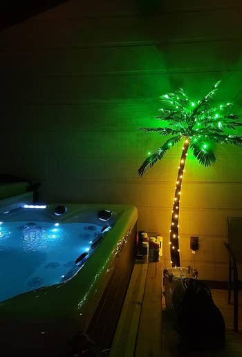 Artificial palm tree with lights next to an outdoor hot tub, suggesting tropical ambiance for home decor