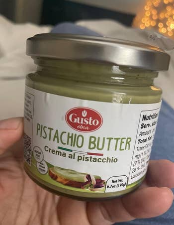 Jar of pistachio food  held successful  hand, labeled 