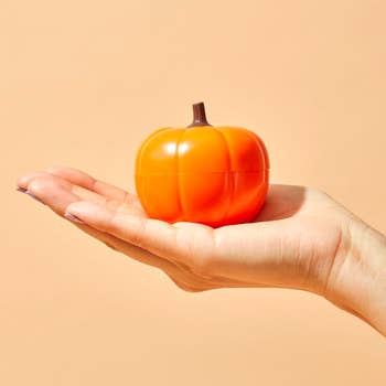 a model holding the pumpkin-shaped jar of eye cream