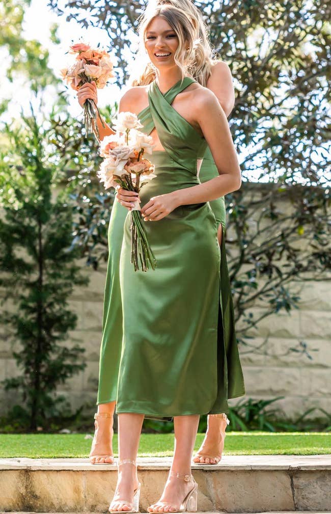 a model posing in the dress while holding a wedding bouquet