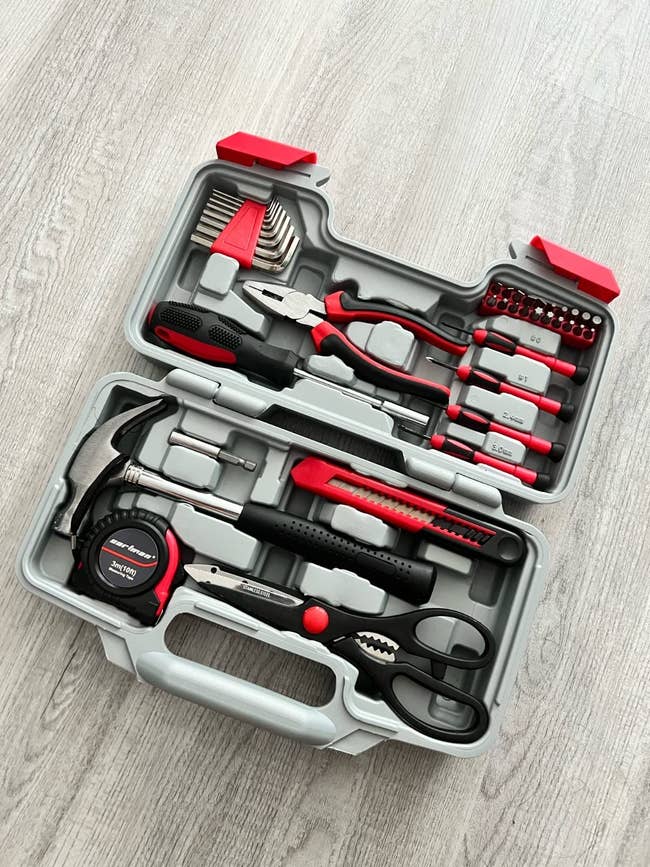 A grey integrative instrumentality lawsuit unfastened to uncover an assortment of tools, including pliers, a hammer, screwdrivers, a portion measure, and hex keys
