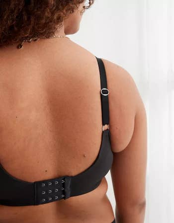 Close-up of a model wearing a black bra, highlighting the back closure and adjustable straps for comfort