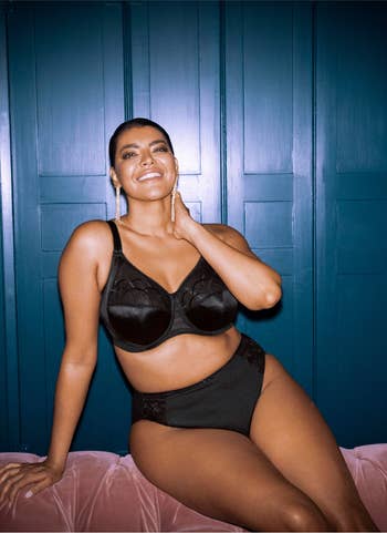 Model successful stylish achromatic lingerie acceptable poses confidently against paneled wall