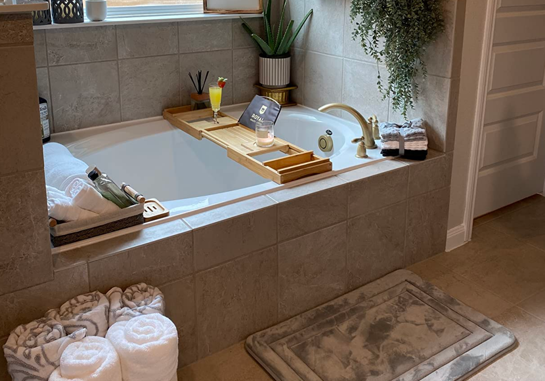 Luxurious bath  country   with a bathtub, woody  tray, bath items, plants, candle, and rolled towels, suggesting a spa-like ambiance  for relaxation