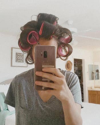 Person with hair in rollers taking a selfie, reflecting modern beauty routine trends