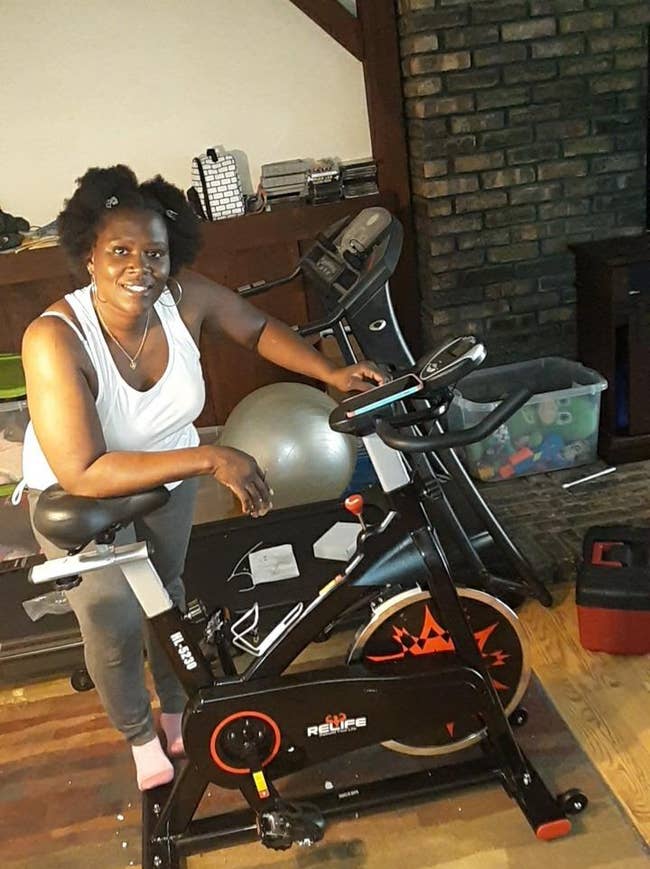 reviewer stands next to black spin bike on floor