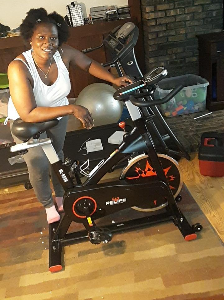 reviewer stands next to black spin bike on floor