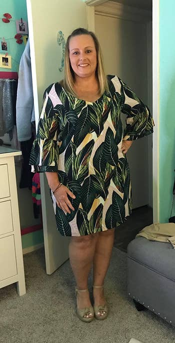 reviewer wearing the dress in green with a leafy pattern