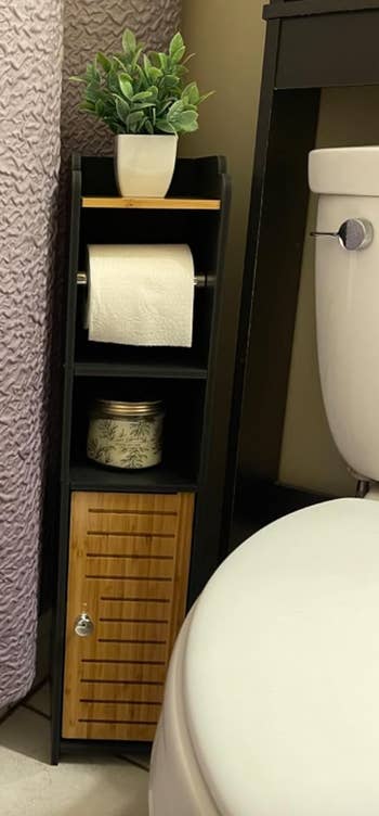 a reviewer's black and brown slim bathroom organizer with a cabinet and toilet paper roll