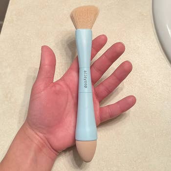 a reviewer holding the brush when it's put together at its largest size