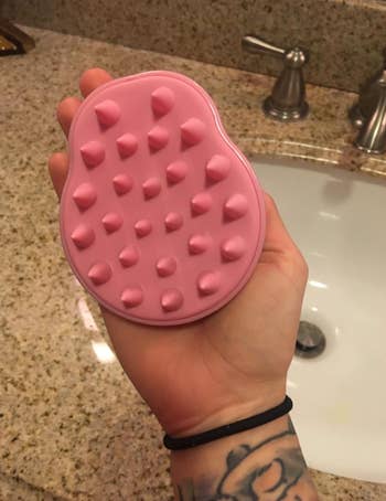 Reviewer holding pink silicone massager in their hand 