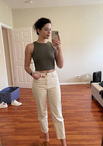 a reviewer wearing the top in khaki green with white jeans 