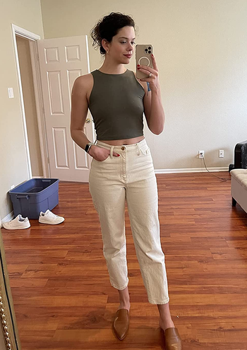 a reviewer wearing the top in khaki green with white jeans 