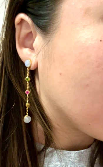brittney wearing drop earrings with colorful stones and gold chain