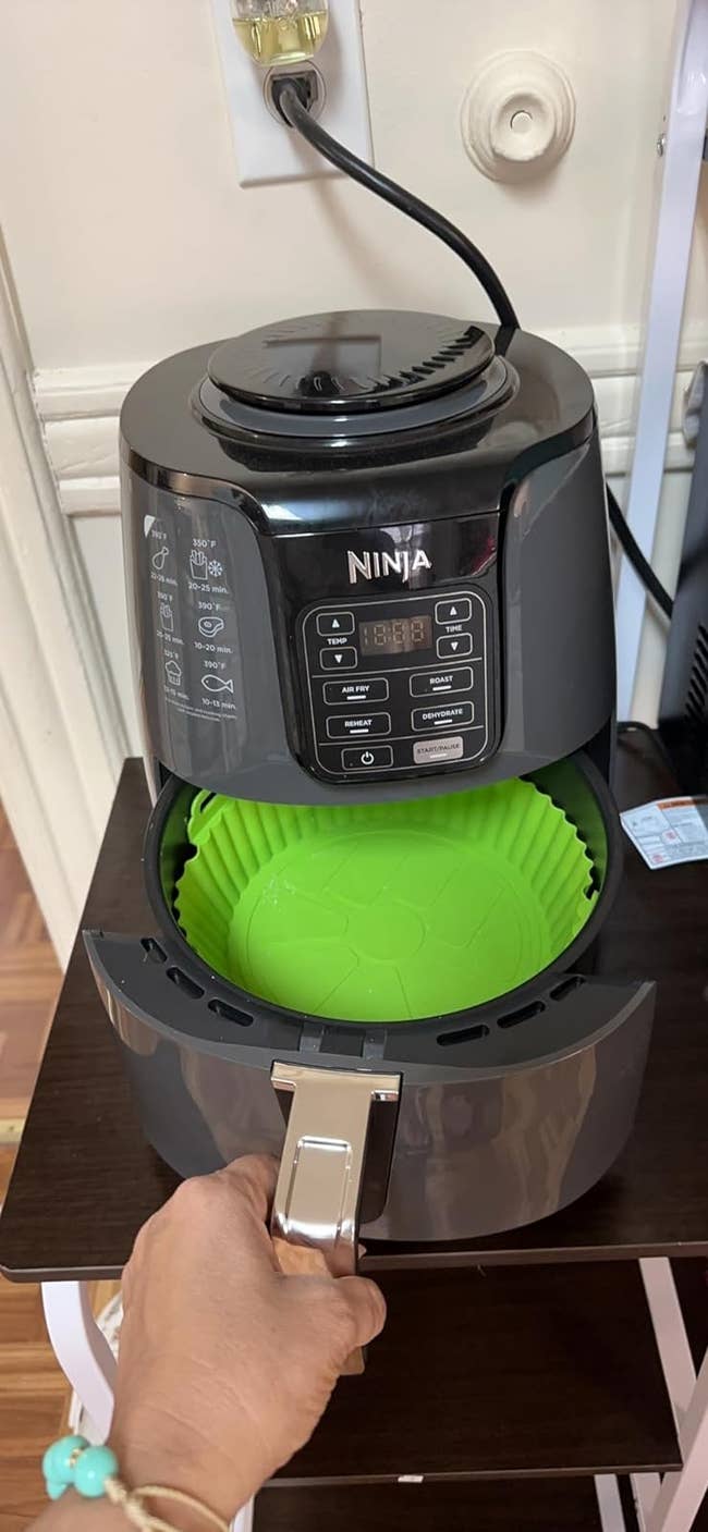An open air fryer with a green silicone liner inside