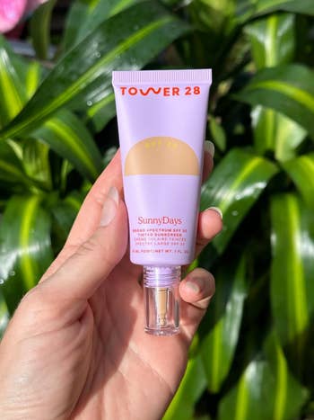 reviewer holding a Tower 28 SunnyDays SPF 30 tinted sunscreen bottle 