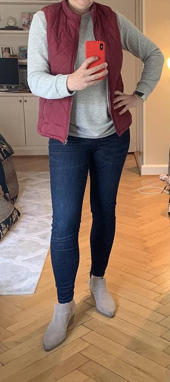 Person wearing a grey  long-sleeve shirt, a quilted vest, acheronian  lavation  jeggings, and ankle boots, lasting  successful  a country   taking a selfie. Face not shown
