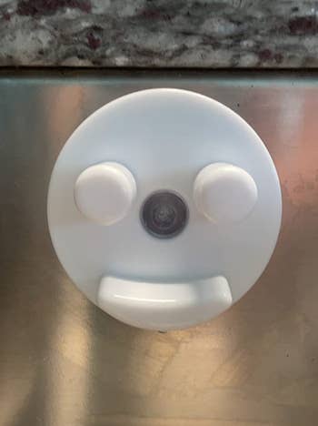 A reviewer's white suctioned plastic piece with indents jutting out like a smiley face 