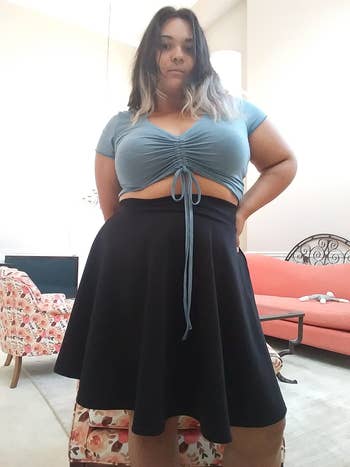 reviewer in light blue drawstring crop top and black flared midi skirt