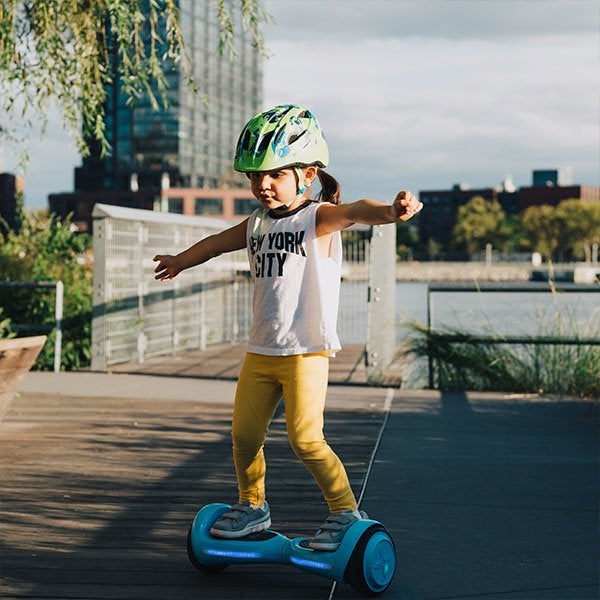 Child model riding blue hoverboard on pavement