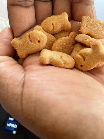 Hand holding respective  tiny  fish-shaped snacks