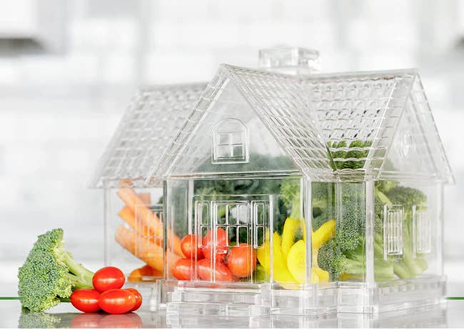A clear house-shaped container full of fresh veggies 