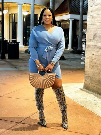 Reviewer wearing the mock wrap dress in a light blue color with snakeskin boots