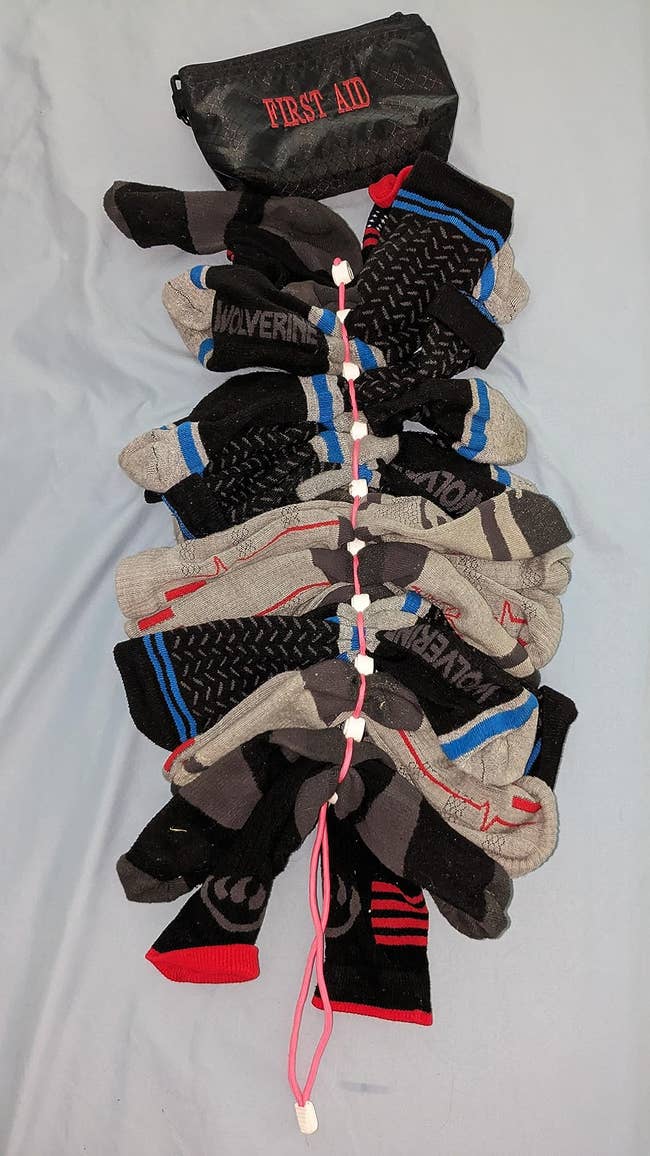 A set of socks neatly clipped together with a pink organizer, next to a labeled First Aid pouch