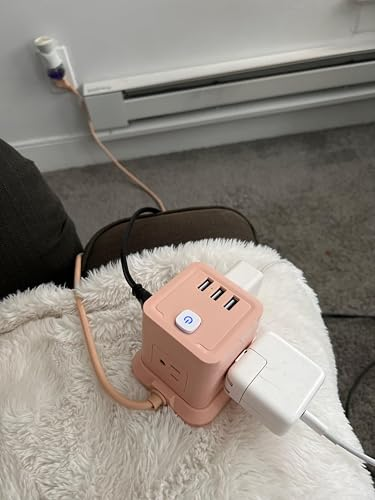 Compact USB power strip with multiple charging ports plugged into an outlet, placed on a blanket-covered surface