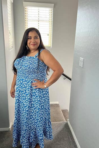 A reviewer poses in a casual blue printed dress with a ruffled hem, suitable for a summer wardrobe