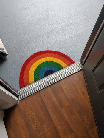 Half-circle rainbow mat at the threshold between a wooden floor and a gray floor