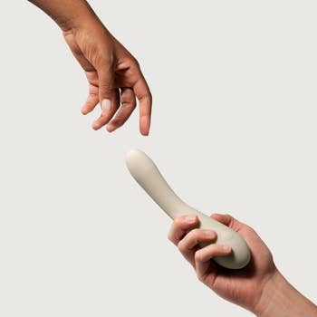 Two hands reaching towards each   other; 1  holds a smooth, ergonomic grey  vibrator