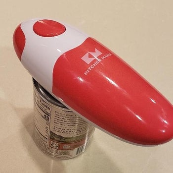 reviewer photo of the red and white can opener on top of a can