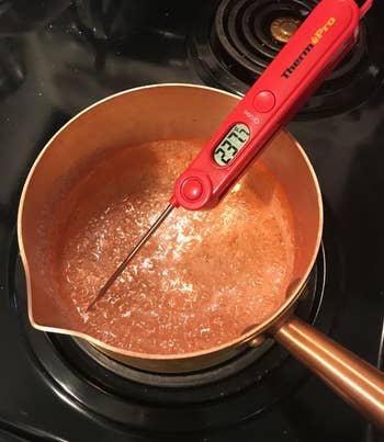 reviewer photo of the red thermometer reading the temperature of a pot filled with boiling sugar