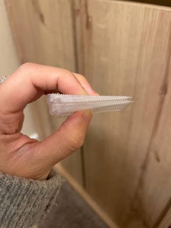 Person holding a translucent integrative clip with interlocking ridges, often utilized for sealing bags