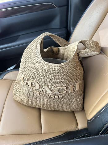 Woven Coach handbag connected  car   seat, featuring the brand's logo successful  ample  letters