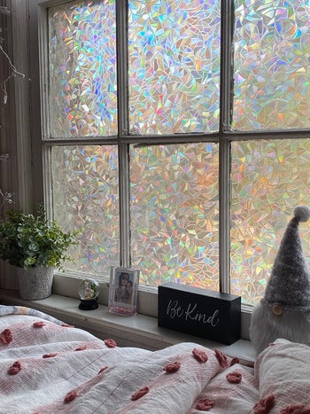 A bedroom window covered in crystal-ish rainbow decorative film 
