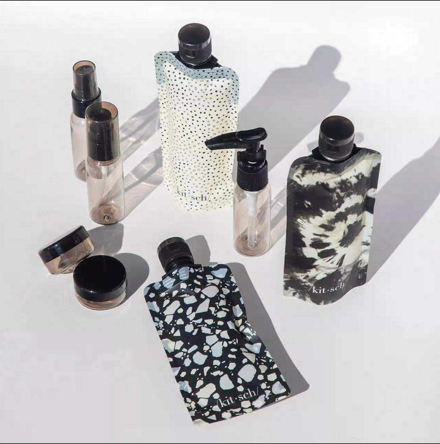 the different containers in black and white patterns and small pump bottle, two spray bottles, and two small containers