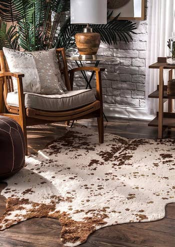 the brown faux cow hide rug in front of a living room chair