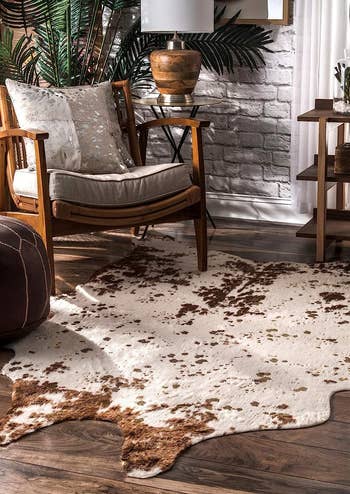 the brown faux cow hide rug in front of a living room chair