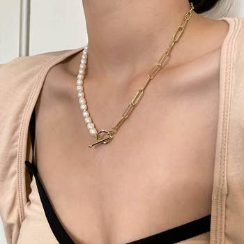 Model wearing a necklace with a chain that is half pearls, half gold links that attaches at the middle 