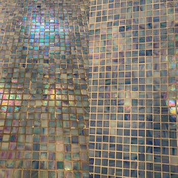 Close-up view of a surface with small, square, iridescent tiles, suggesting luxurious decor elements
